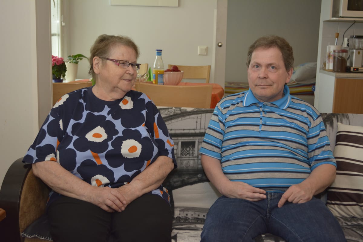 Iäkäs äiti ja hänen poikansa istuvat sohvalla