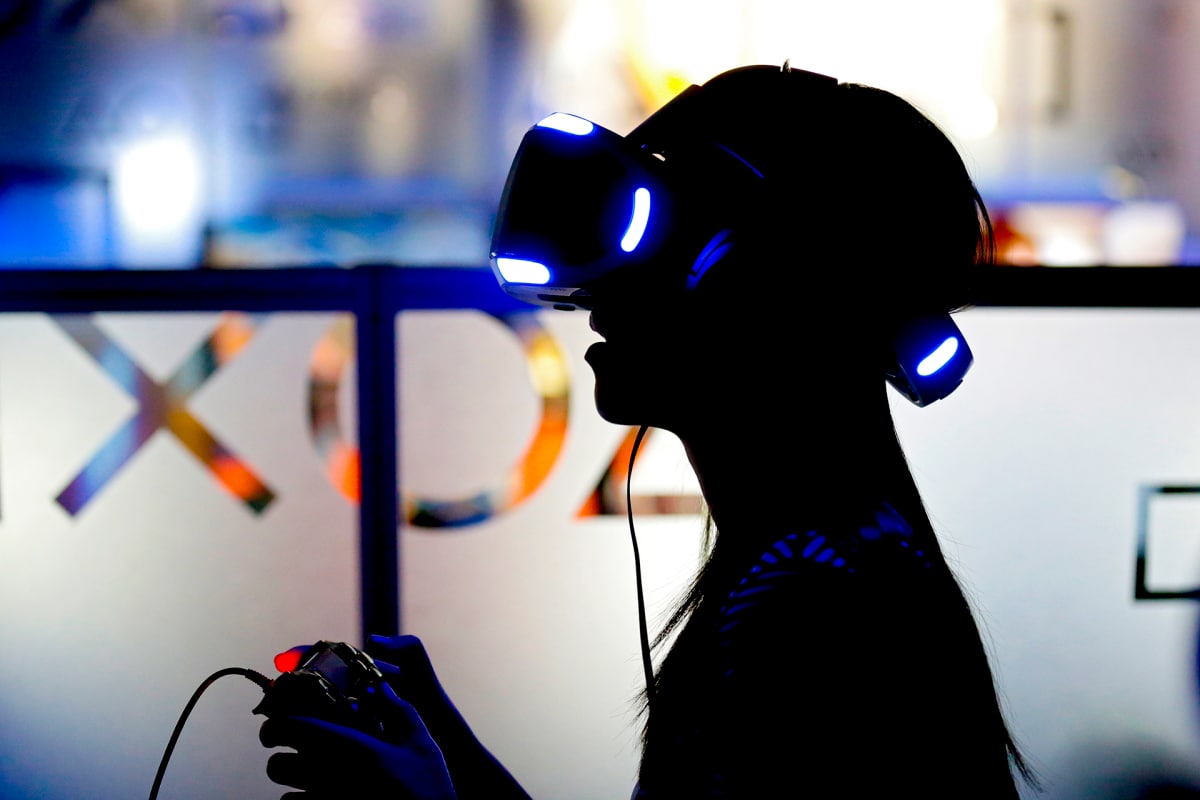 Henkilö virtuaalilasit päässään ja konsoliohjain käsissään.