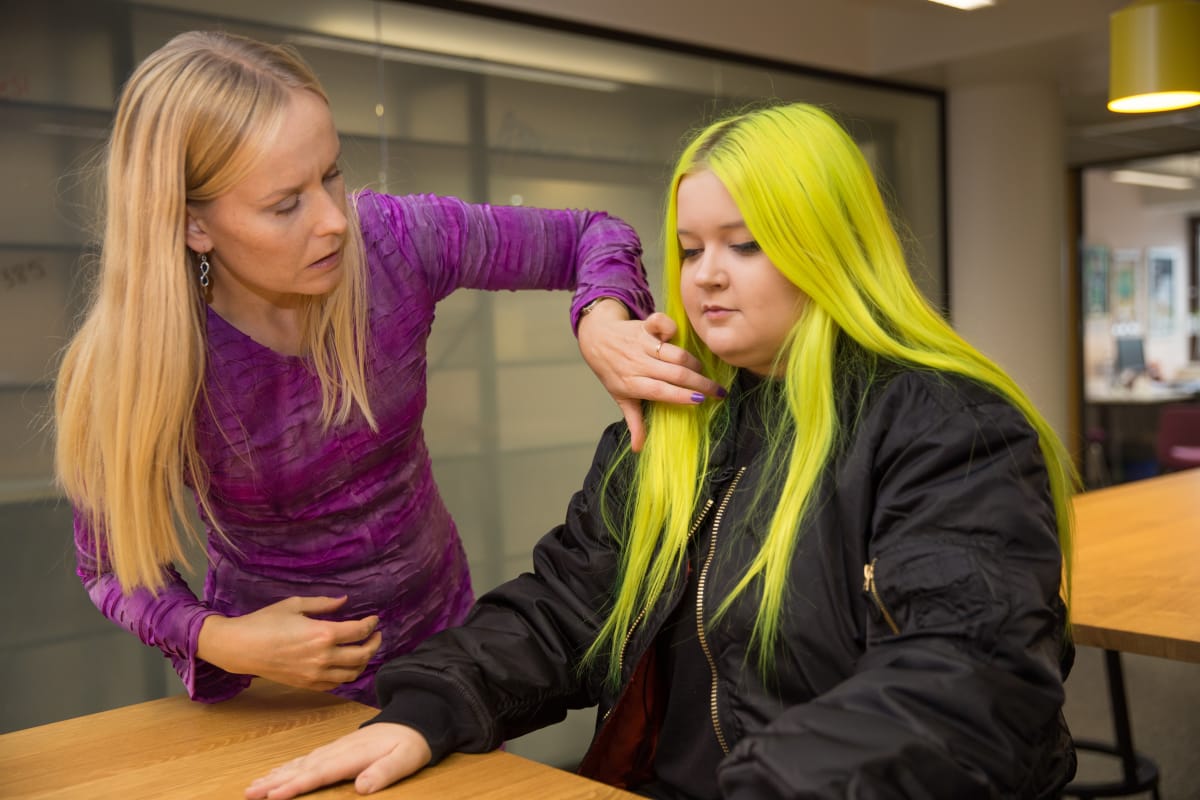 Ylen kuvaaja Nella Nuora laittaa mikrofonia Almalle.
