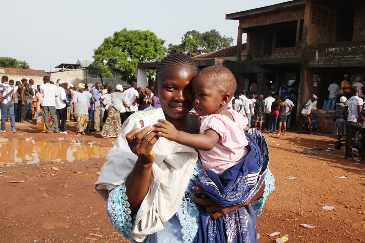 Äiti ja lapsi presidentinvaalien äänestyspaikan edustalla Free Townissa, Sierra Leonessa, marraskuussa 2012.