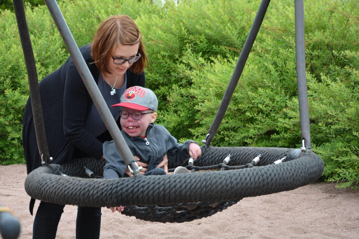 Äiti keinuttaa kehitysvammaista poikaansa.