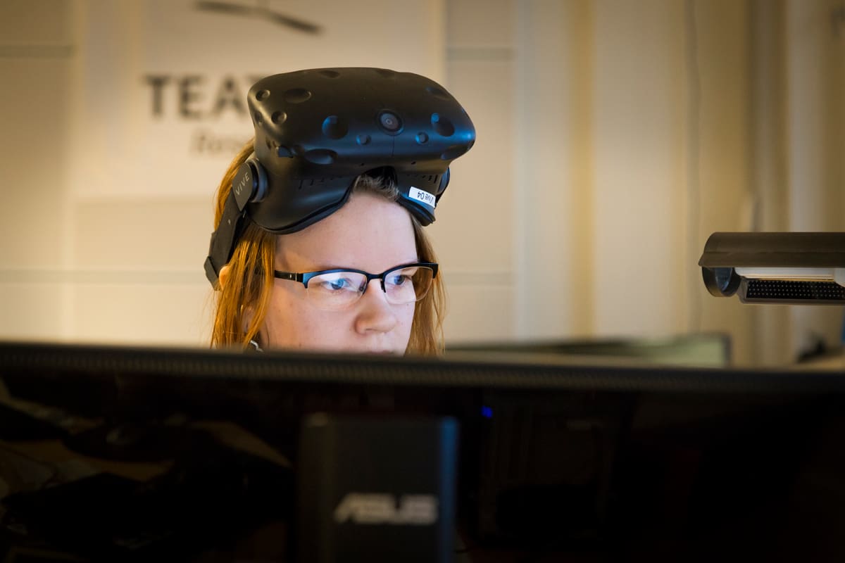 Naine virtuaalilasit otsalla tietokoneen ääressä.