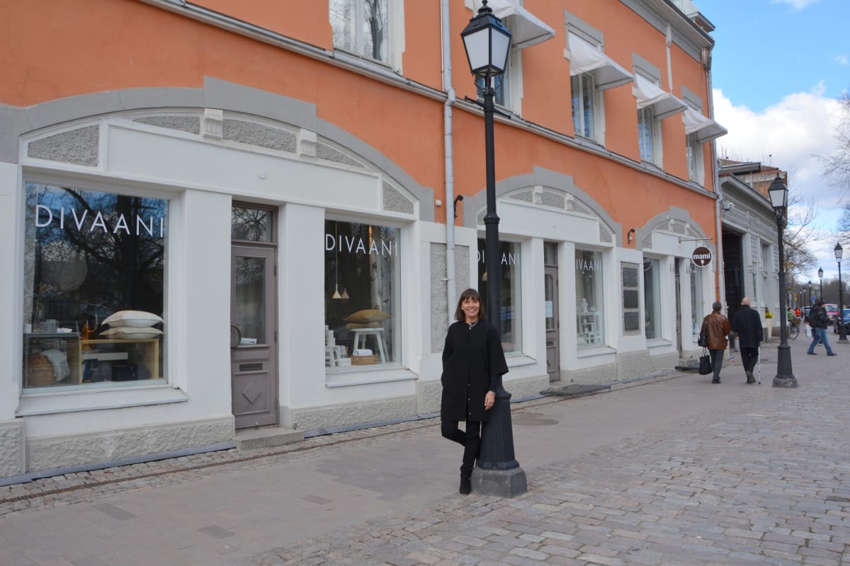 nainen nojaa katulamppuun