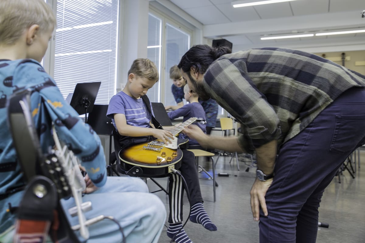 Joel Runne saa Ali Muradilta oppia kitaran käsittelyyn.