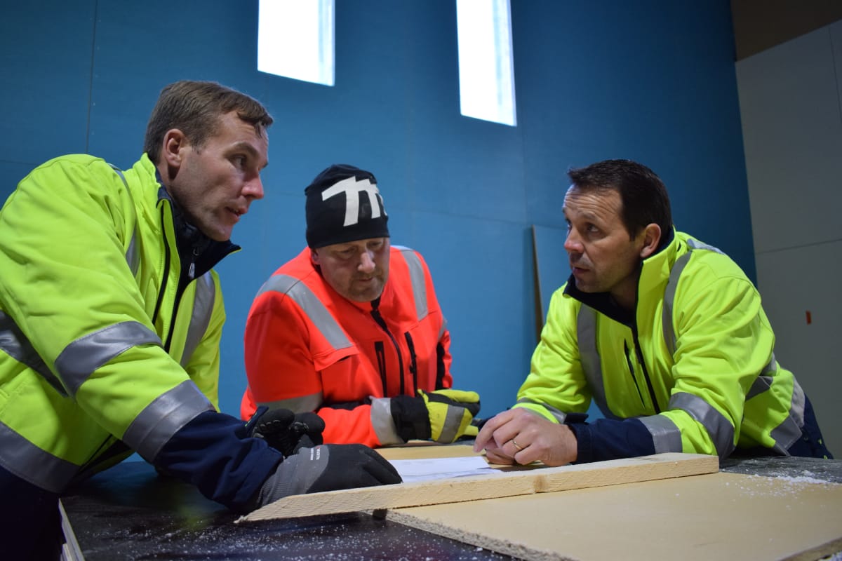 Vesa Rantanen, Ville Arkkila ja Paavo Kallio pitävät palaveria monitoimihallin rakennustyömaalla.