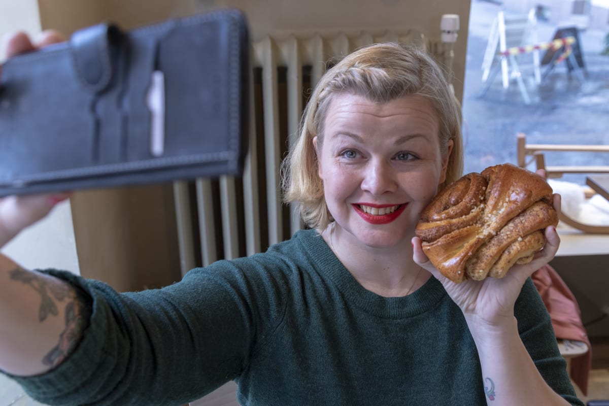 Kirjailija Ani Kellomäki ottaa selfien korvapuusti kädessään.