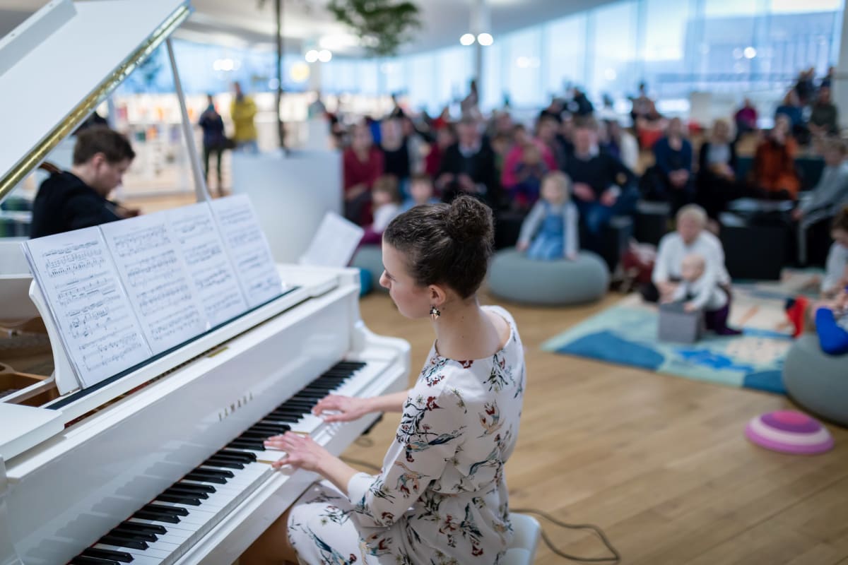 Sellisti Jussi Makkonen (vas) ja pianisti Nazig Azezian (etualalla) soittamassa lapsiperheyleisölle, Keskustakirjasto Oodi, 28.2.2019.