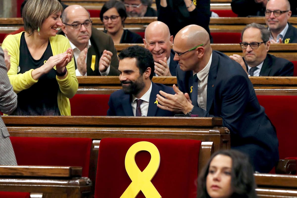 Roger Torrent istuu parlamenttisalissa. Ympärillä muut edustajat taputtavat.