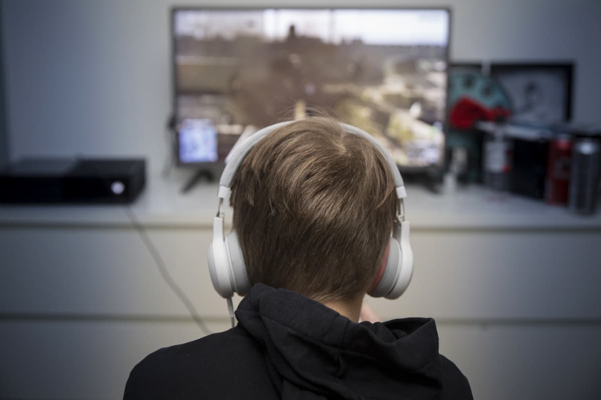poika pelaa tietokonepeliä kuulokkeet päässä