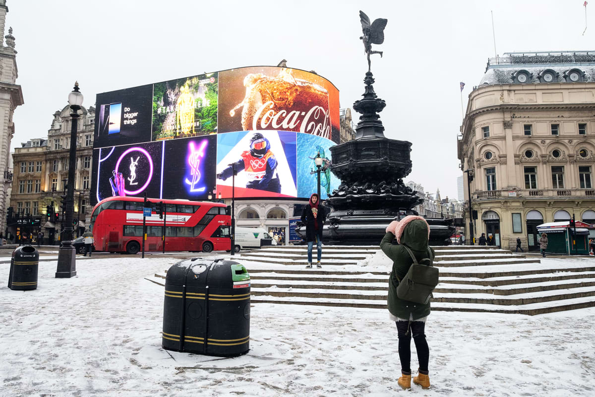 Turistit ottavat kuvia lumisella Piccadilly Circuksella.