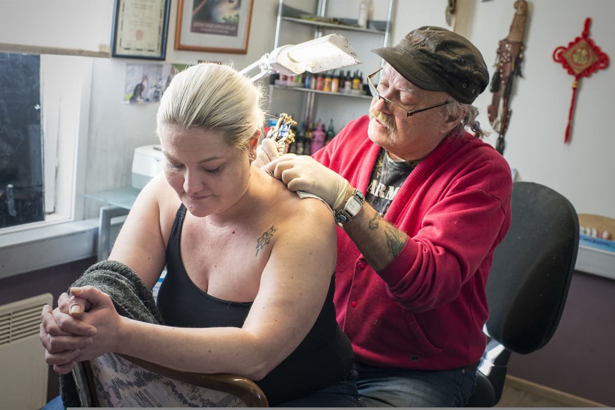 Mies tekee naiselle tatuointia.
