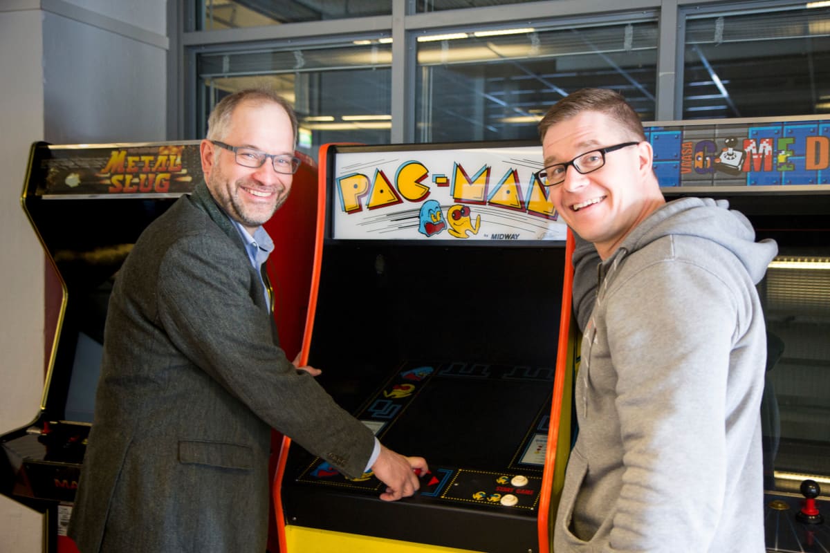 Taloustieteen professori Panu Kalmi ja pelitutkija Olli Raatikainen ikonisen Pac-Man -pelin äärellä.