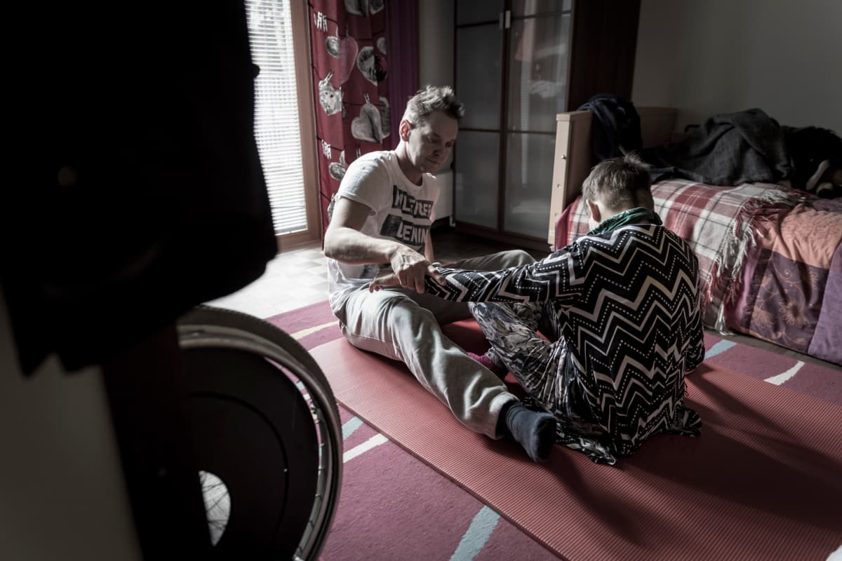 Kehitysvammainen Laura Saari ja fysioterapeutti Ville Laine jumppaavat lattialla
