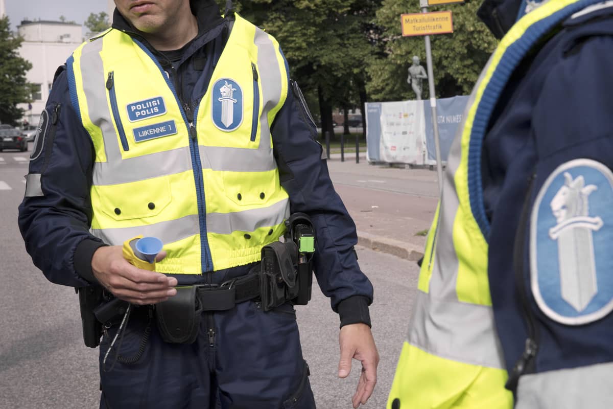 Poliisi kädessään alkometri.