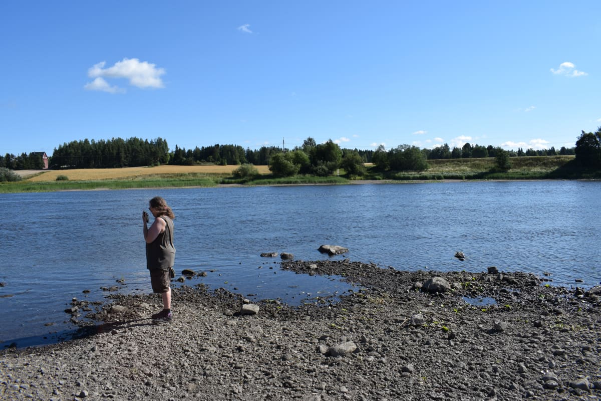 Nainen joenrannalla.