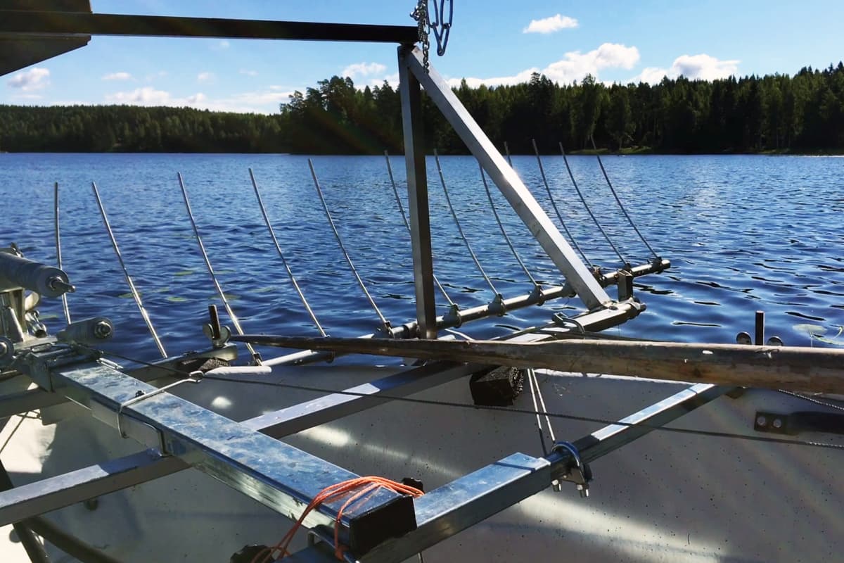 Veneen keulaan on liitetty Vexi Hoppulan kehittämä keruuharava, jolla leikattu kasvillisuus työnnetään rantaan.