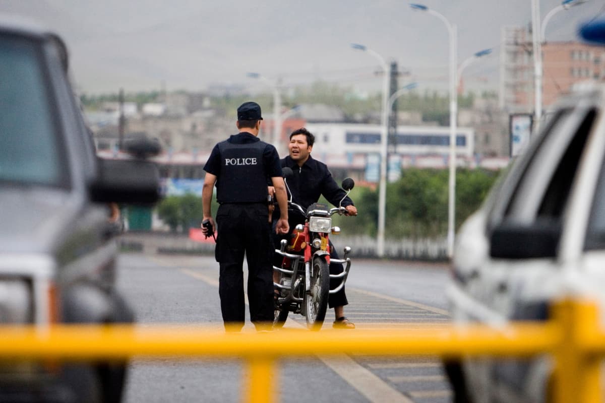 epa01795075 A police officer stops an ethnic Uighur man on a motorcycle in a predominantly Uighur area in Urumqi, Xinjiang province, China, 15 July 2009. Ten days after the 05 July 2009 deadliest unrest since the 1970's, the number of security forces in Urumqi seems to be diminishing with daily routine slowly returning to the region at the same time. EPA/DIEGO AZUBEL