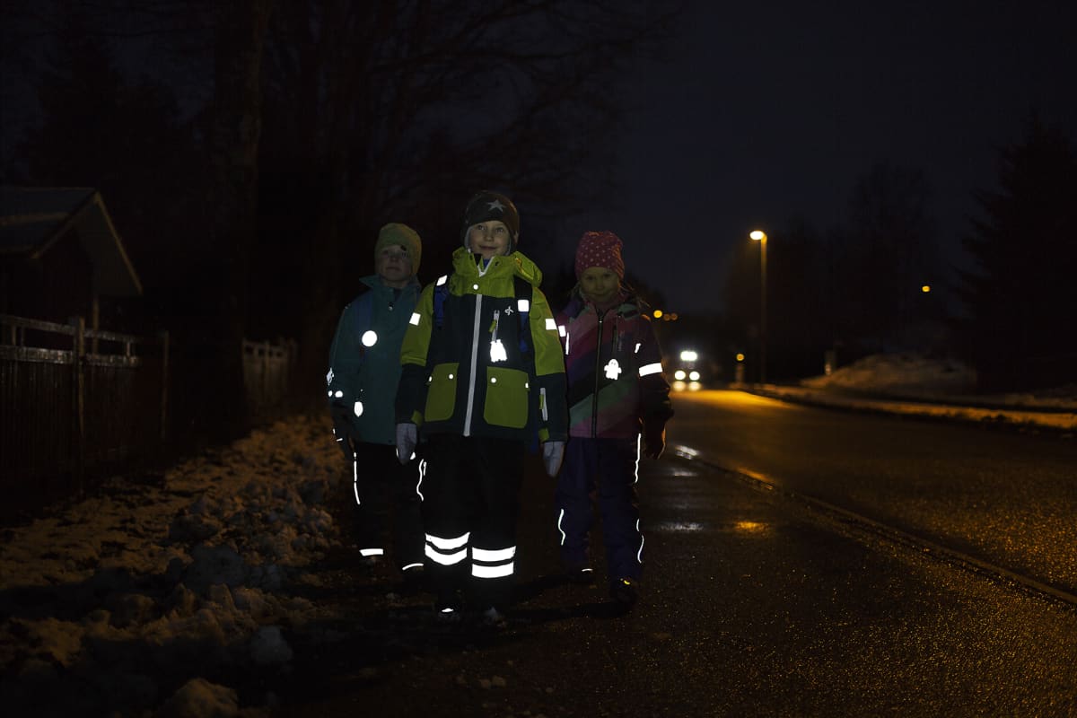Heijastinta käyttäviä lapsia pimeällä kadulla.