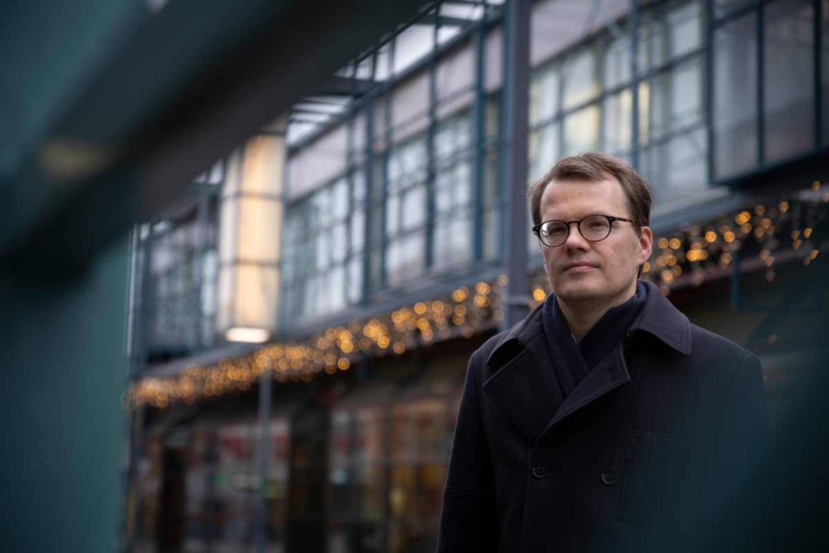 Kristo Vesikansan taustalla näkyy teräsrakenteita, jotka luovat rakennuksen jälkikonstruktivistisen ilmeen.