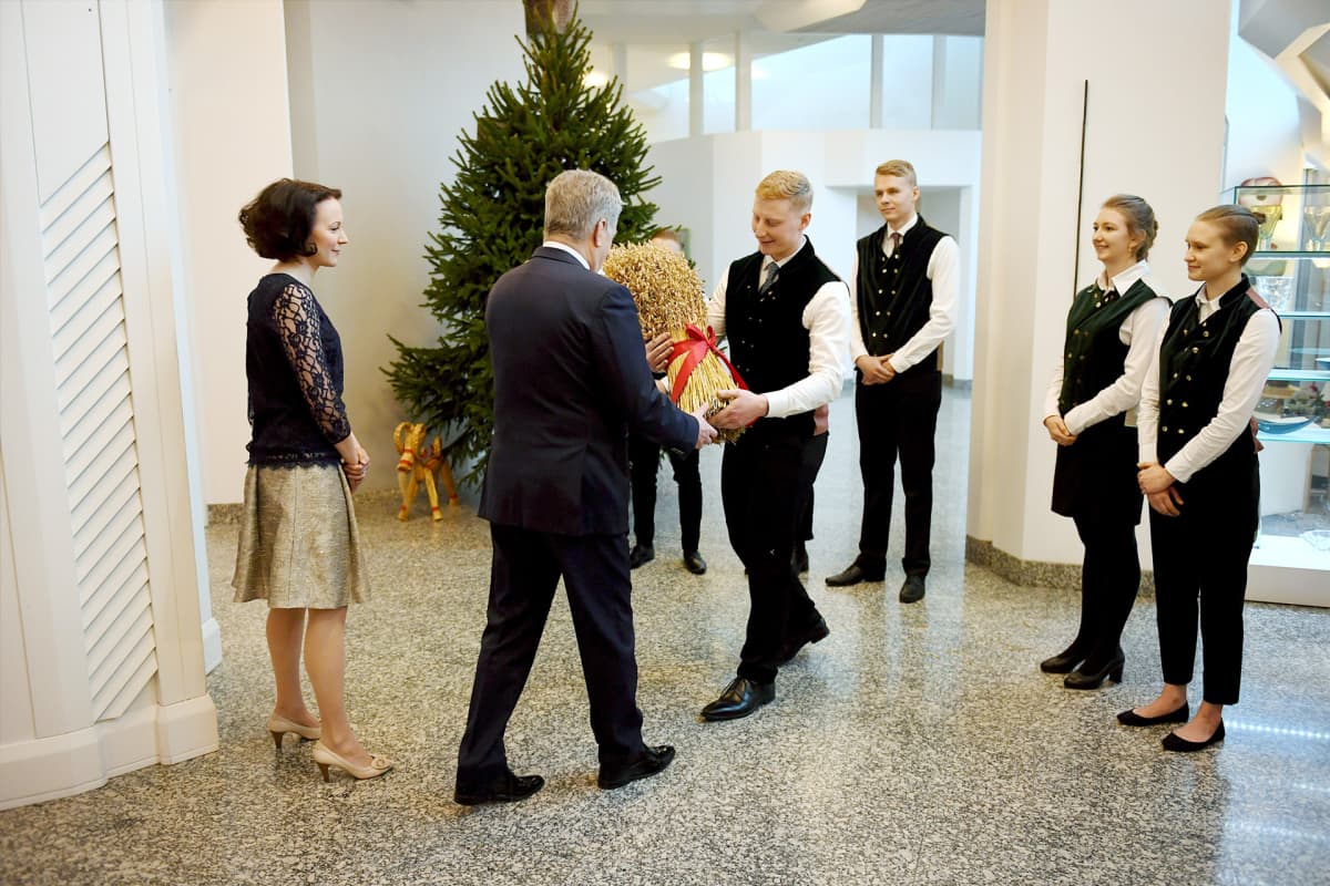 Sauli Niinistö ja Jenni Haukio vastaanottavat metsäylioppilaiden lahjoittaman joulukuusen presidentin virka-asunnolla.