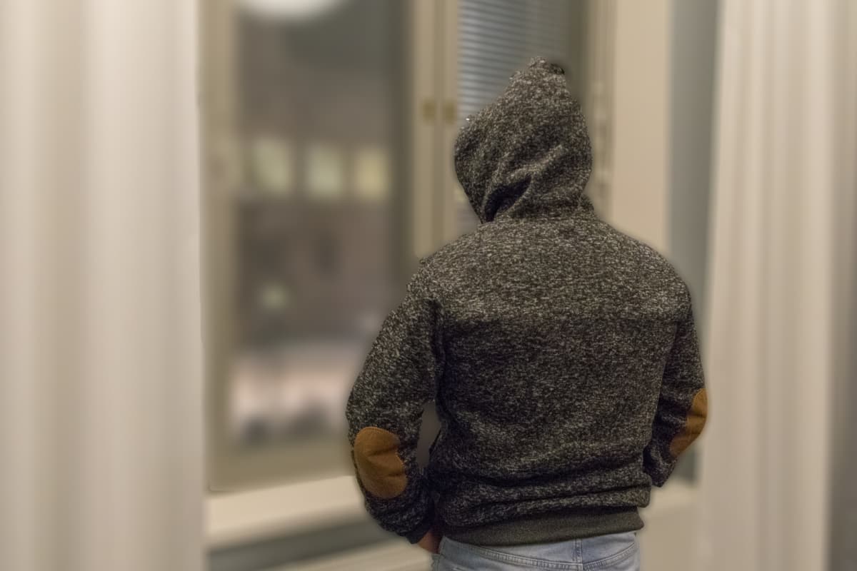 Anonyymi henkilö katsoo ikkunasta ulos.