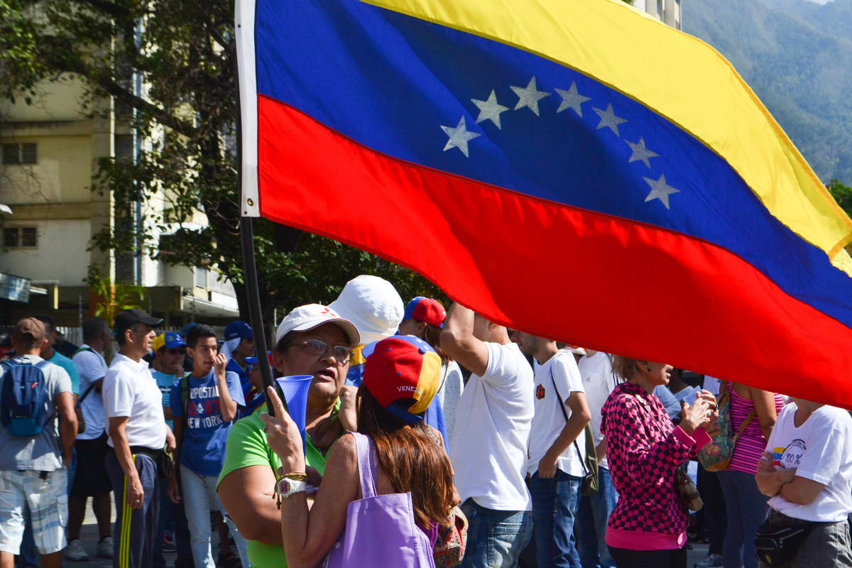 Mielenosoittajia ison Venezuelan lipun kanssa.
