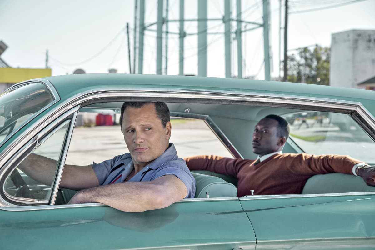 Näyttelijät Viggo Mortensen ja Mahershala Ali Green Book -elokuvassa. Elokuvastillissä valkoinen mies toimii autonkuljettajana mustalle pianistille 1960-luvun Yhdysvalloissa.