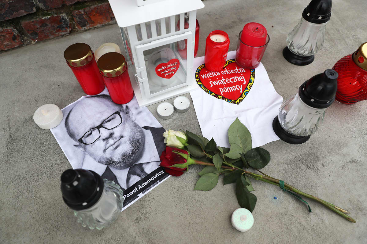 Kukkia ja kynttilöitä puukotetun pormestarin valokuvan ympärillä