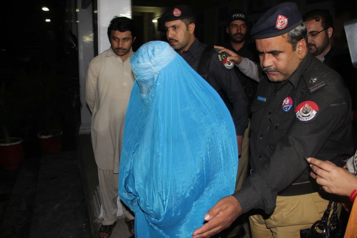Poliisit saattavat burkhaan pukeutunutta naista.