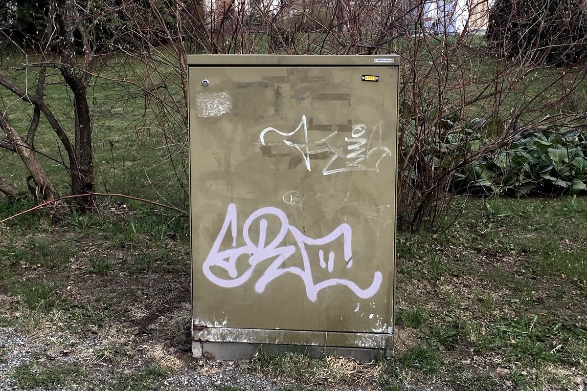Kadunvarressa on nuhjuinen, pohjaväriltään ruskea sähkökaappi.