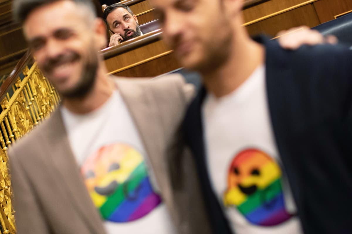 Mies puhuu puhelimessa kahden miehen selän takana.