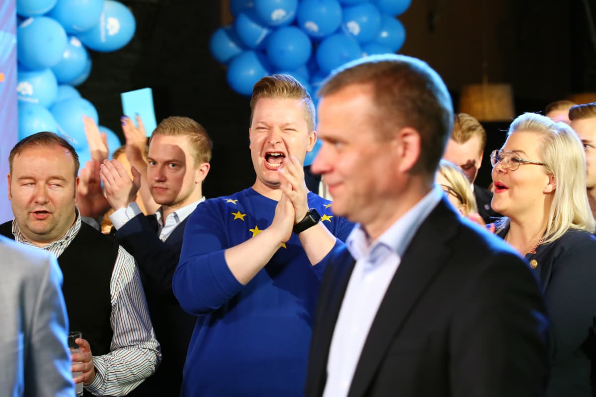 Kalle Lahtinen ja Piia Kurki taputtavat Petter Orpon taustalla kokoomuksen vaalivalvojaisissa.