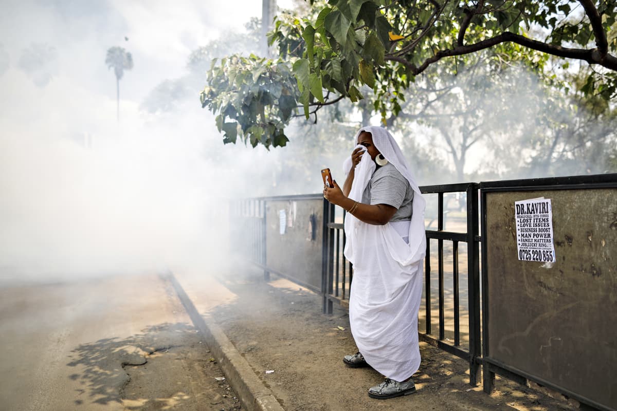 Sudanilainen nainen peittää kasvonsa sen jälkeen, kun poliisi on levittänyt kyynelkaasua Kenian Nairobissa 19. kesäkuuta.