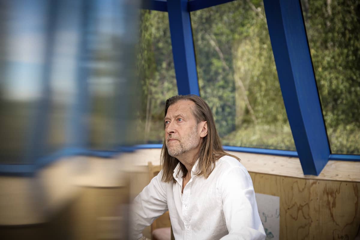 Taiteilija Jan-Erik Andersson istuu Lehtitalon ikkunan ääressä.