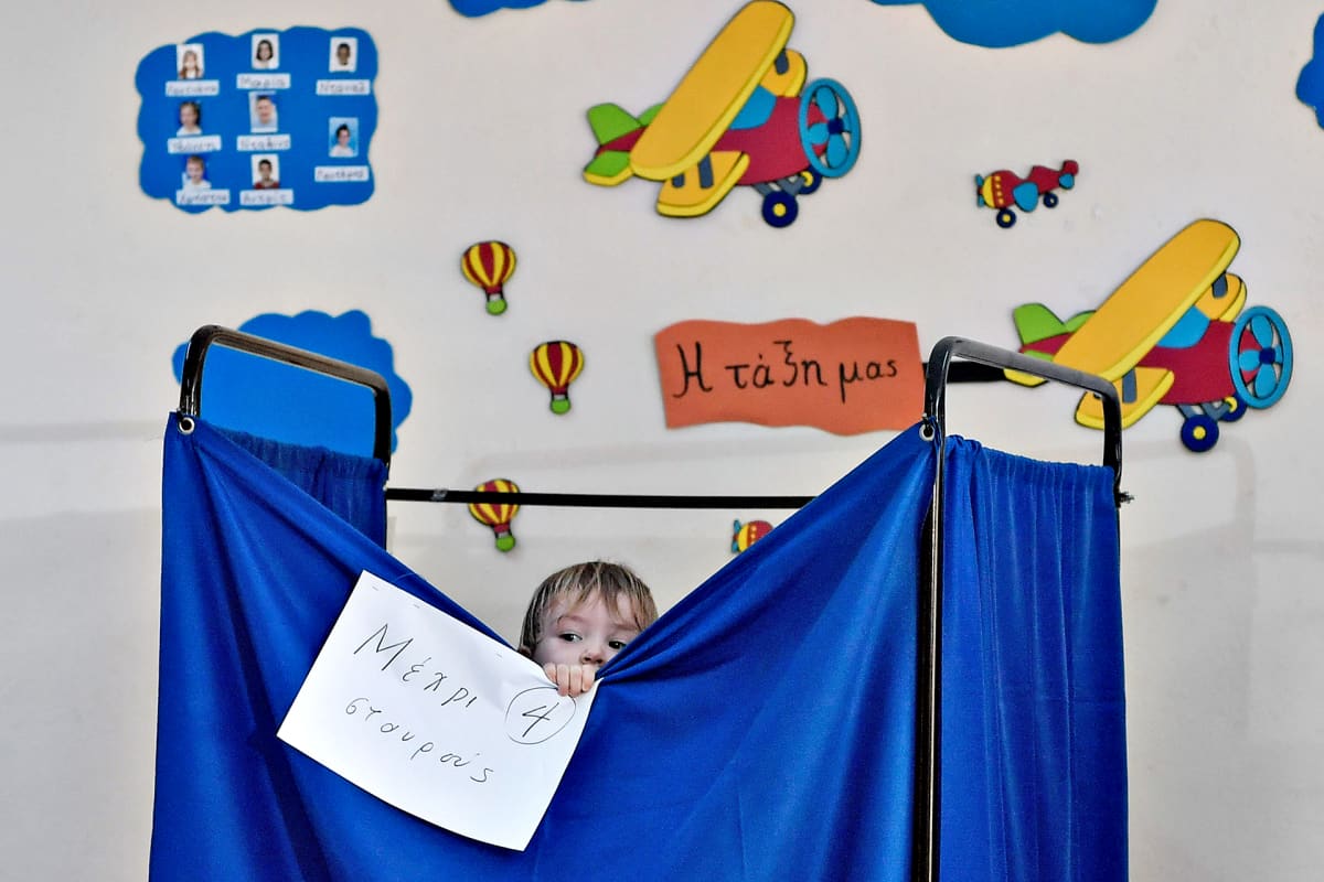 Lapsi vilkuilee ulos äänestyskopista Kreikan Ateenassa 7. heinäkuuta 2019.