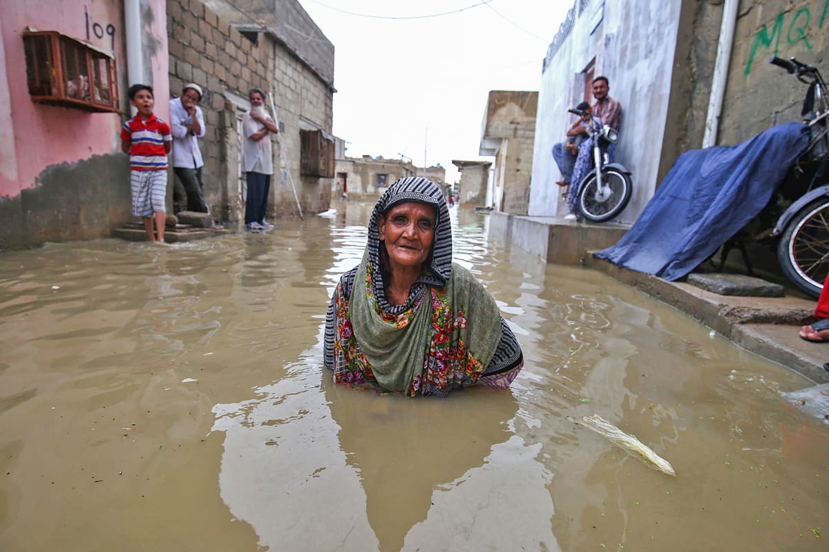 Vanha nainen seisoo tulvaveden valtaamalla kadulla kainaloita myöten monsuuni-sateiden aikana Karachissa, Pakistanissa.