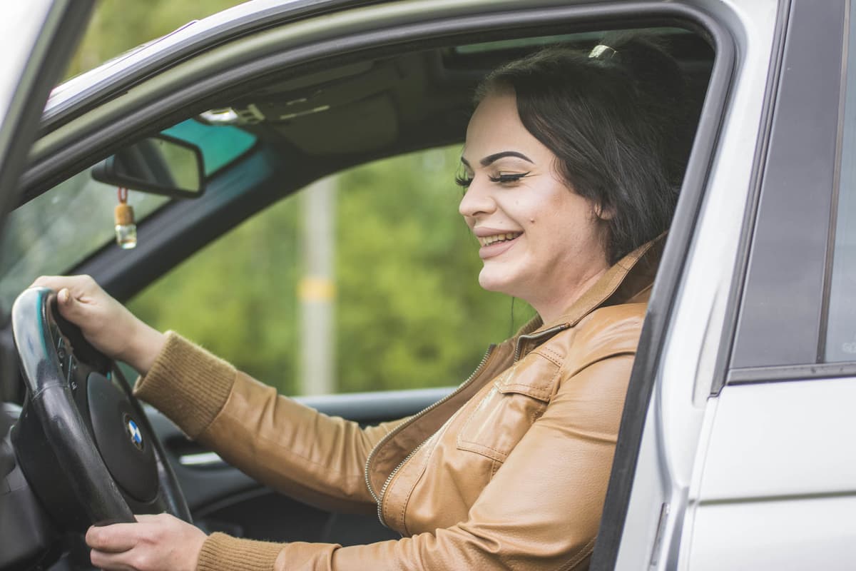 Victoria Karppinen istuu kuljettajan paikalla autossa ja nauraa