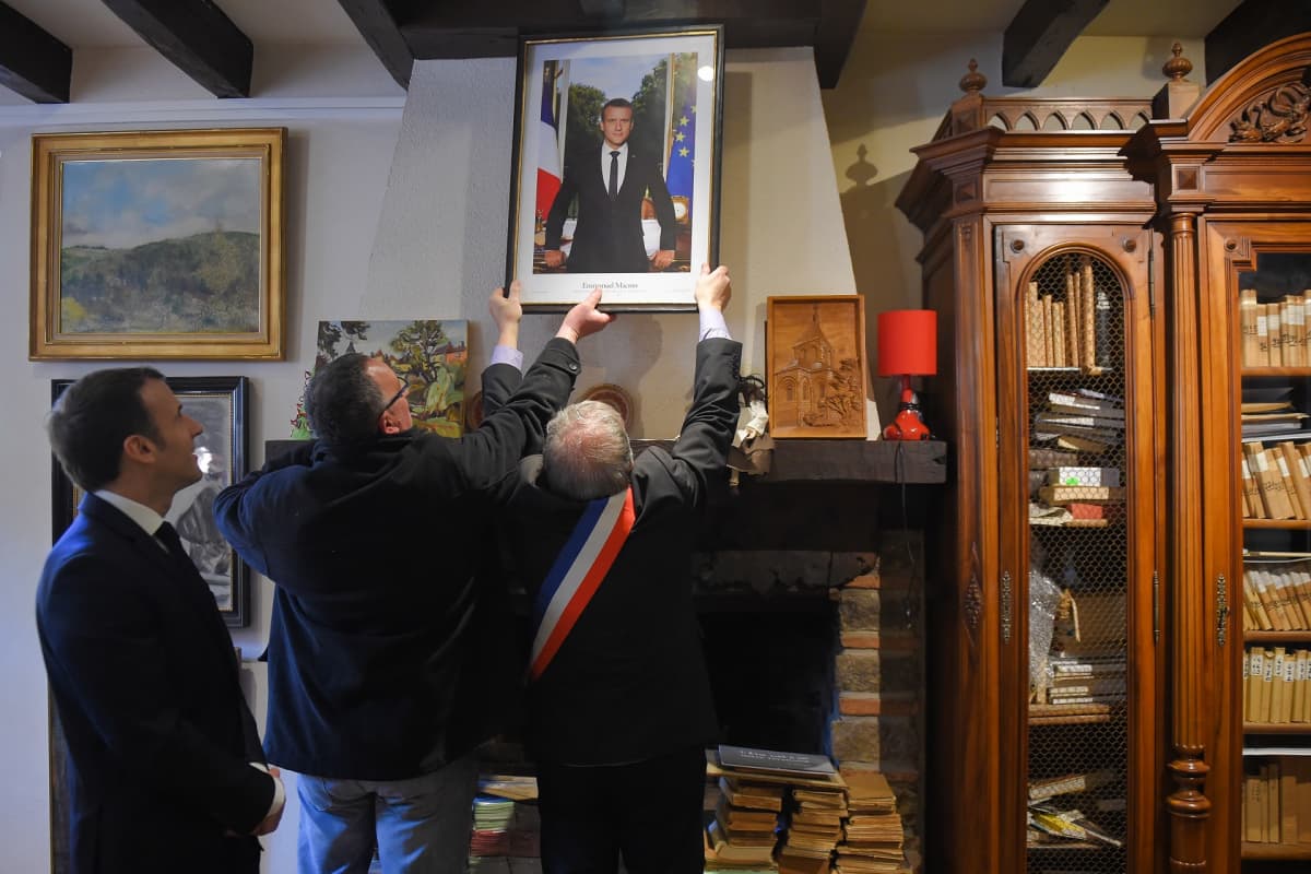 Emmanuel Macron katselee kuvansa ottamista alas seinältä.