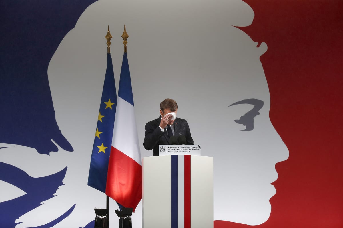 Ranskan presidentti Emmanuel Macron pyyhkii kasvojaan ennen puhettaan muistotilaisuudessa, jossa kunnioitettiin Pariisin veitsihyökkäyksessä surmansa saaneita poliiseja.