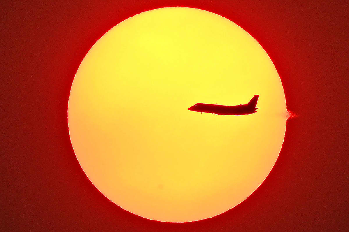 Lentokone kuvattuna laskevaa aurinkoa vasten Australian Sydneyssa.