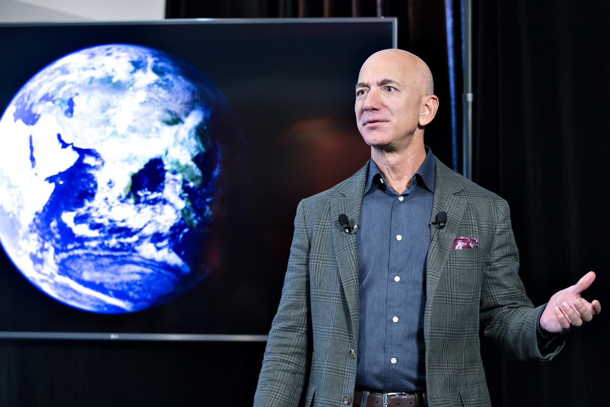 Jeff Bezos pitää puhettaan. Taustalla on maapallo kuvattuna avaruudesta.