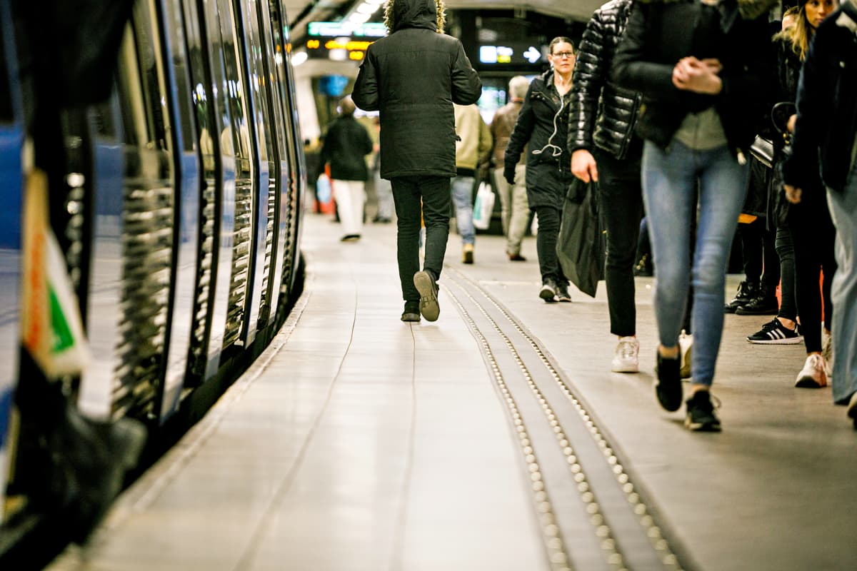 Ihmisiä kävelee metrolaiturilla.