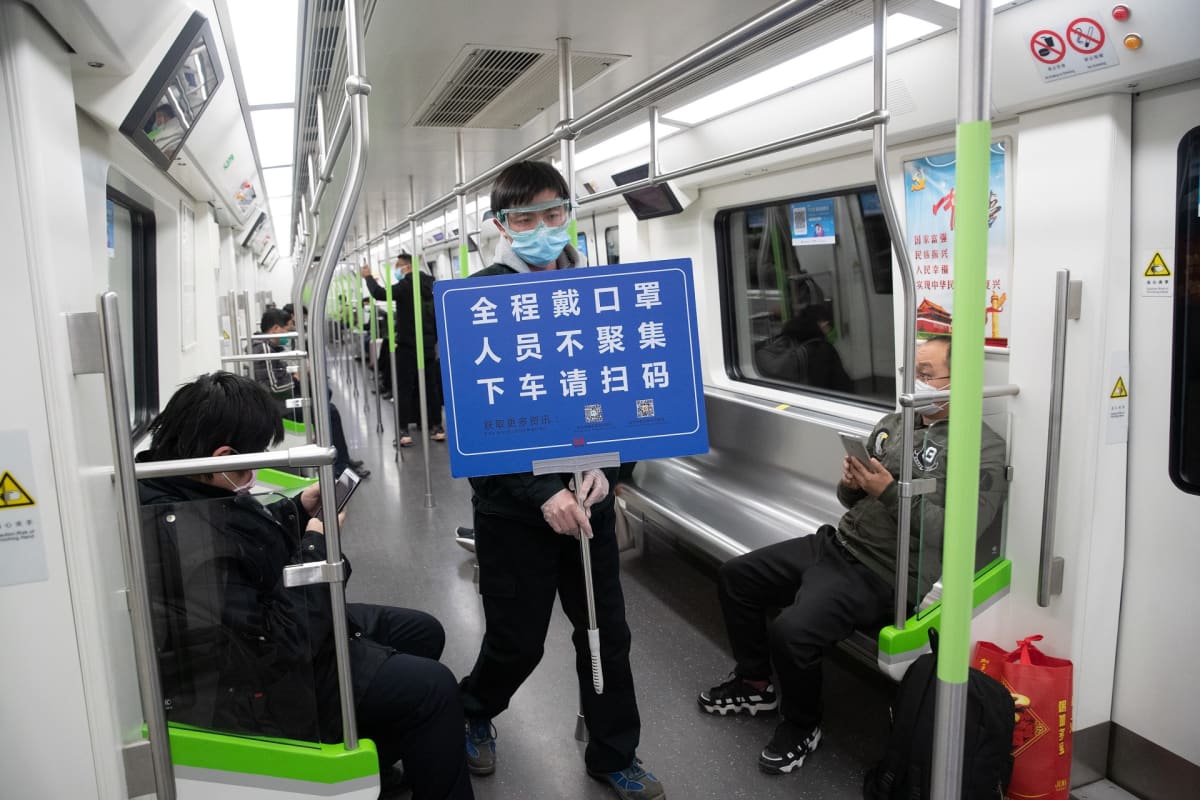 Wuhanin metron työntekijä kantaa ohjekylttiä.
