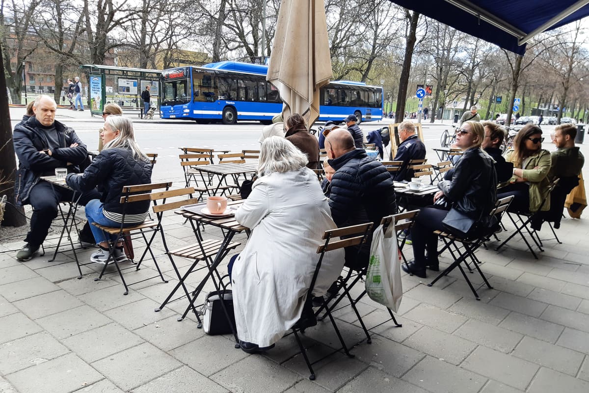 Ihmiset nauttivat kahvilan ulkoterassilla.