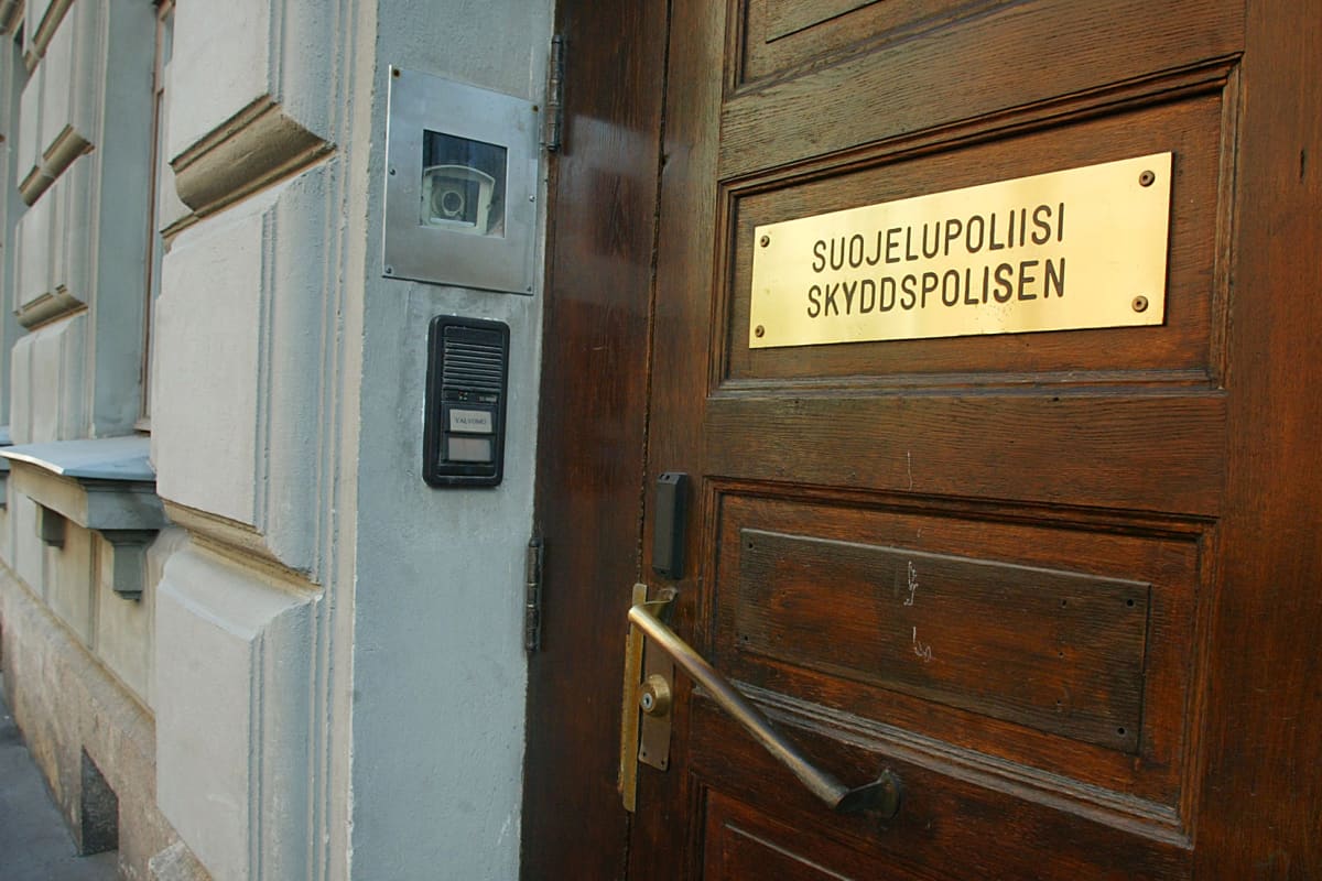 Kuvassa on Suojelupoliisin kyltti ovessa.