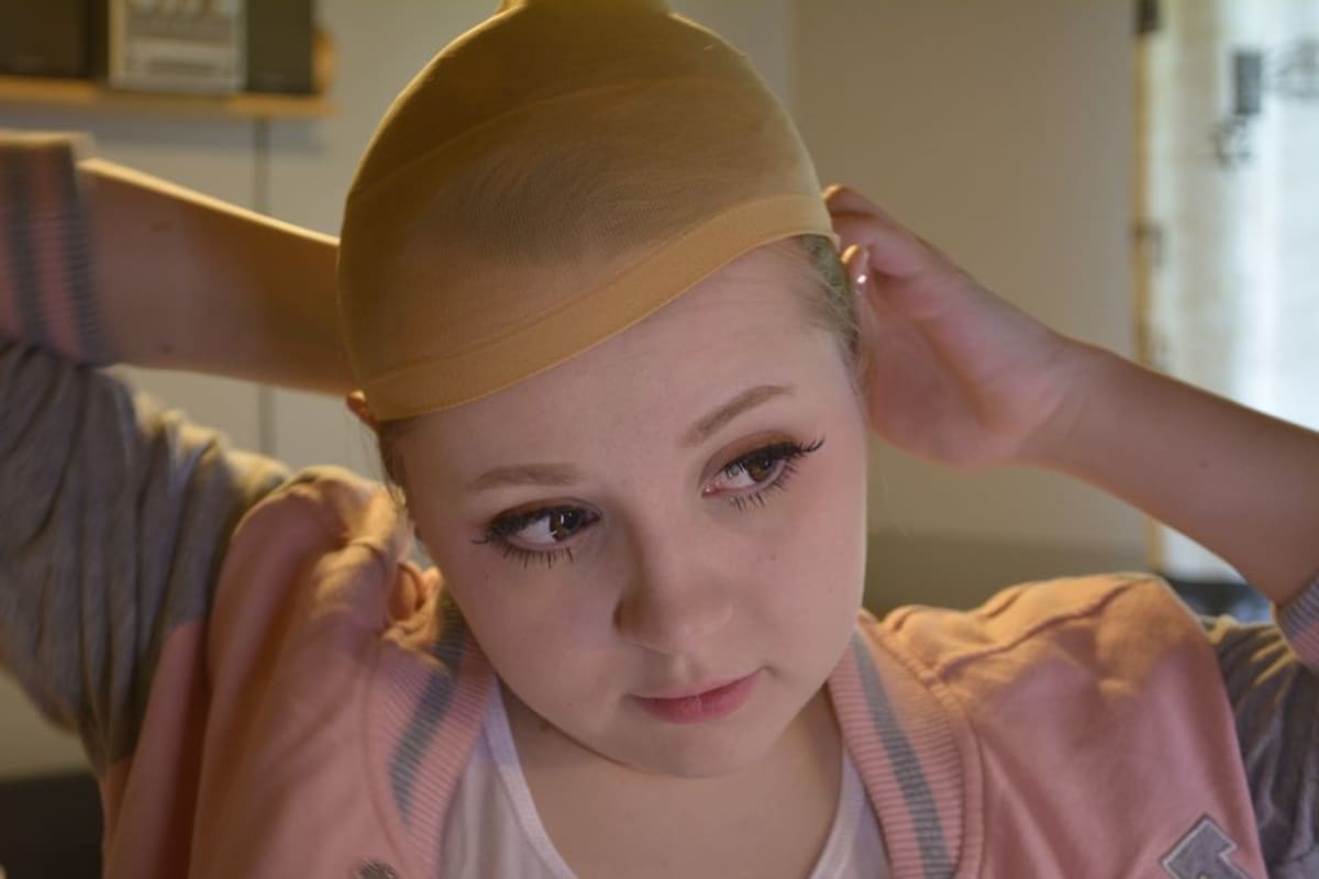 Anette Pitkänen asettaa peruukkisukkaa päähän ennen Desuconia