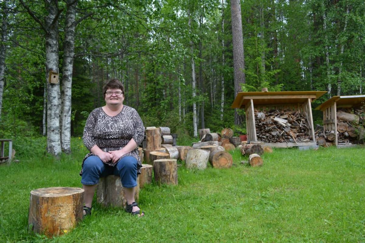 Miia Korhonen istuu laitoskotinsa takapihalla puupölkyllä.