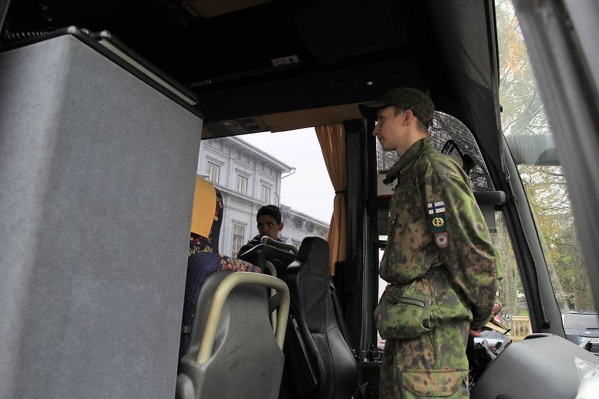 Pikkupoika ja varusmies hiljaisina bussin keulassa.