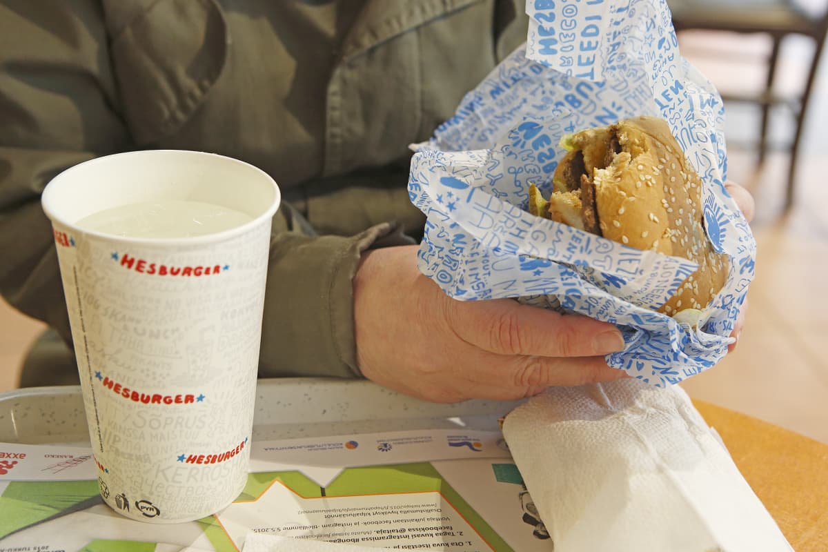 Mies syö hampurilaista Hesburgerissa.