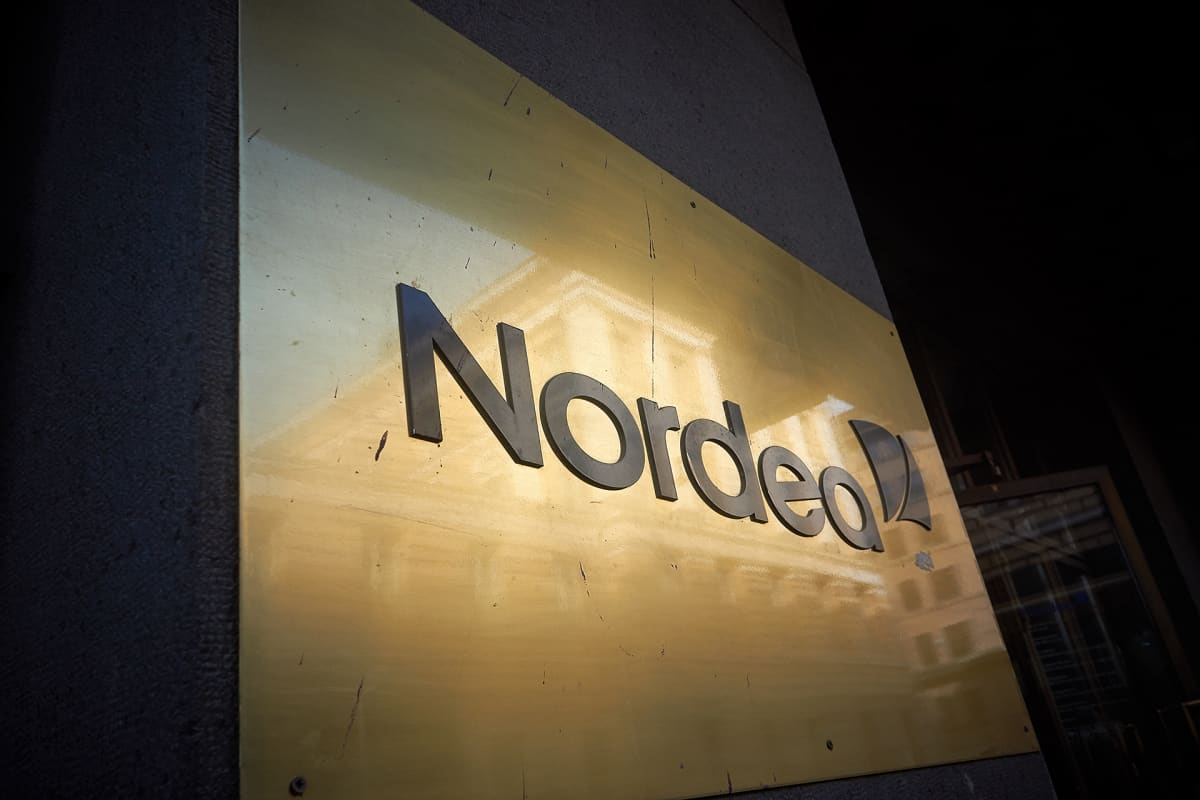Nordean kultainen kyltti Aleksanterinkadun pankkikonttorin edessä Helsingissä. Heijastuksena näkyy Helsingin yliopiston päärakennus.